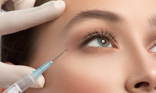 Close up of female eye area getting botox injection by syringe
